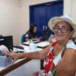 Mulher sorrindo realiza cadastro com funcionário em evento Governo Presente em Manaus.