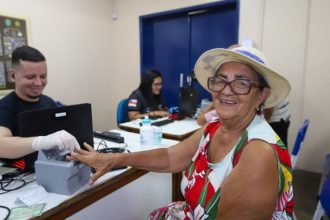 Mulher sorrindo realiza cadastro com funcionário em evento Governo Presente em Manaus.
