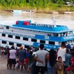 Navio do INSS atracado para atendimento móvel na região amazônica, com pessoas reunidas no local.