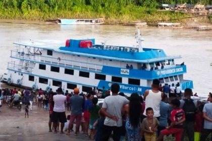 Navio do INSS atracado para atendimento móvel na região amazônica, com pessoas reunidas no local.