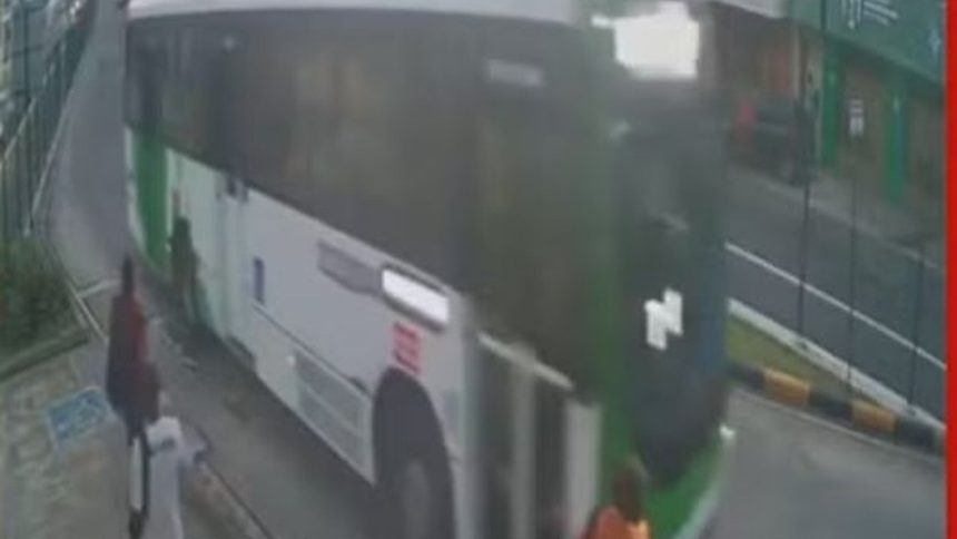 Ônibus branco e verde em movimento em via pública, com pessoas próximas e uma pessoa atropelada