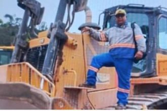 Operador de máquina em frente a trator, possivelmente local do acidente que causou sua morte por afogamento.