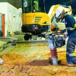 Operários trabalham em obras de saneamento em Manaus, utilizando máquinas e ferramentas.