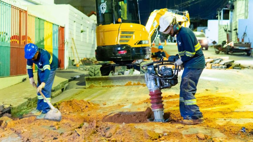 Operários trabalham em obras de saneamento em Manaus, utilizando máquinas e ferramentas.