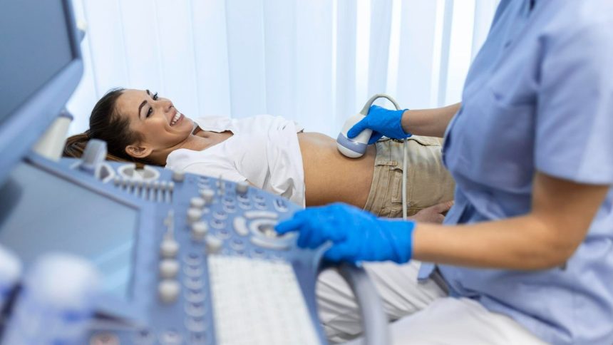 Paciente sorrindo durante exame de ultrassom abdominal com médico utilizando equipamento.