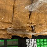 Pacotes de substância marrom em sacos plásticos transparentes sobre uma balança digital.