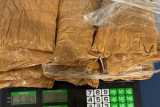 Pacotes de substância marrom em sacos plásticos transparentes sobre uma balança digital.
