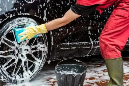 Pessoa lavando pneu de carro preto com esponja e sabão.