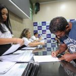 Pessoas assinando documentos em evento da CNH Social no Amazonas.