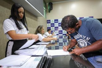 Pessoas assinando documentos em evento da CNH Social no Amazonas.