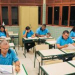 Pessoas em sala de aula, possivelmente preenchendo formulários, em evento do Sesc.