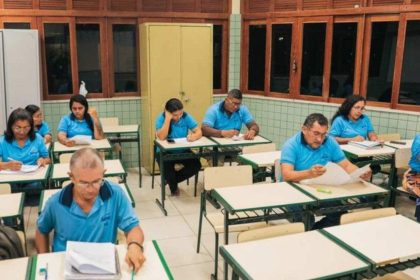 Pessoas em sala de aula, possivelmente preenchendo formulários, em evento do Sesc.