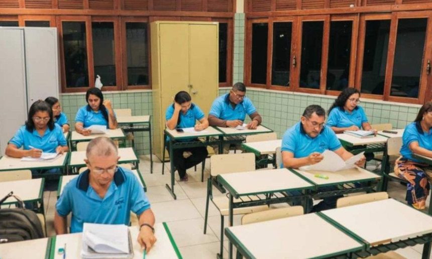 Pessoas em sala de aula, possivelmente preenchendo formulários, em evento do Sesc.