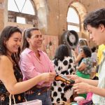 Pessoas em um evento de vendas, uma mulher pagando com cartão.