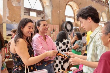 Pessoas em um evento de vendas, uma mulher pagando com cartão.