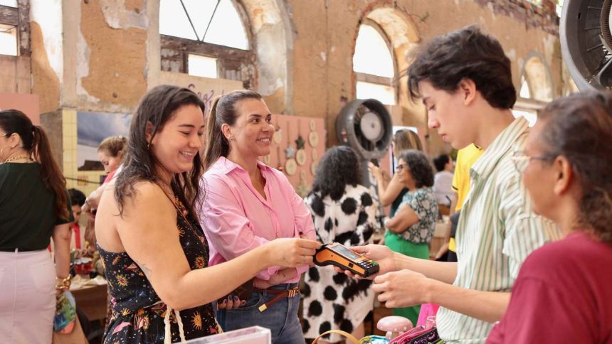 Pessoas em um evento de vendas, uma mulher pagando com cartão.