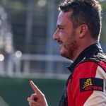 Piloto amazonense sorrindo e apontando com o dedo, com uniforme de corrida.