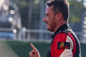 Piloto amazonense sorrindo e apontando com o dedo, com uniforme de corrida.