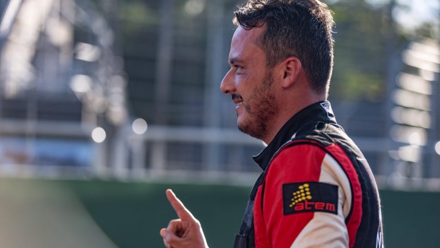 Piloto amazonense sorrindo e apontando com o dedo, com uniforme de corrida.