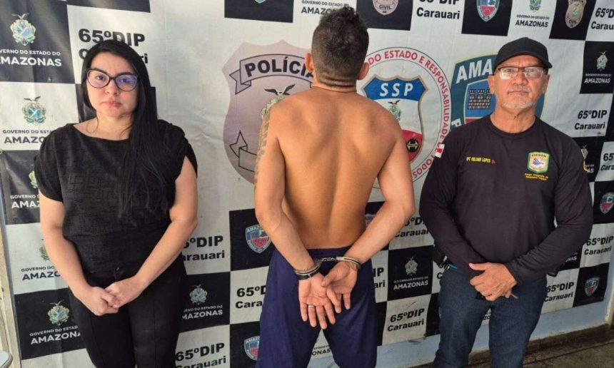 Polícia prende homem de 29 anos em Carauari, Amazonas. Ele está algemado entre dois policiais.