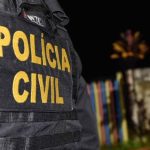 Policial civil com colete tático, cena de investigação noturna.