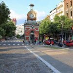 Praça com relógio de torre, carros e pessoas em Manaus.