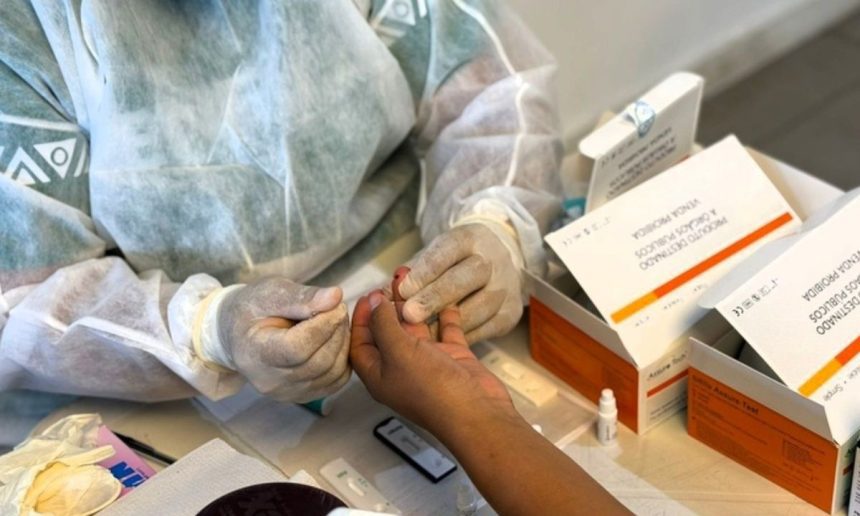 Profissional de saúde realizando teste rápido em paciente, usando luvas e jaleco.