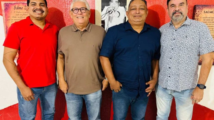 Quatro homens sorrindo, posando juntos. Um deles está com uma camisa vermelha para discutur o Carnaval 2026 de Manaus