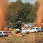 Redemoinho de poeira em Brasília com carros ao fundo.
