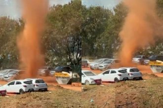 Redemoinho de poeira em Brasília com carros ao fundo.