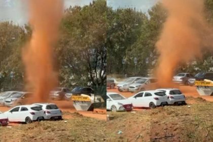 Redemoinho de poeira em Brasília com carros ao fundo.