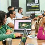 Reunião de trabalho com pessoas analisando dados em laptops, provavelmente sobre questões ambientais.