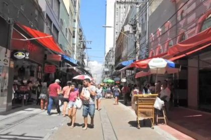 Rua movimentada em Manaus com pessoas caminhando e lojas.