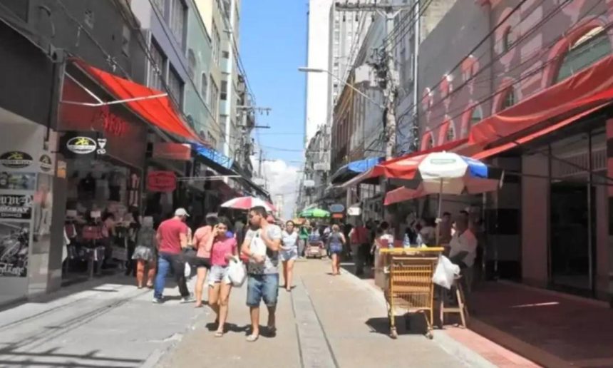 Rua movimentada em Manaus com pessoas caminhando e lojas.