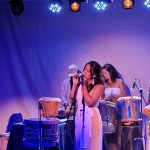 Show musical com instrumentos e sons da Amazônia, com destaque para a cantora principal e músicos.