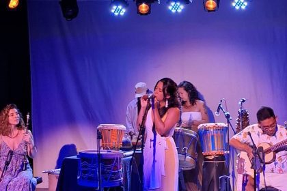 Show musical com instrumentos e sons da Amazônia, com destaque para a cantora principal e músicos.