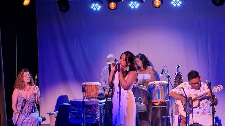 Show musical com instrumentos e sons da Amazônia, com destaque para a cantora principal e músicos.