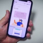 Smartphone com tela do PROUNI em primeiro plano, com detalhes sobre bolsas de estudo.