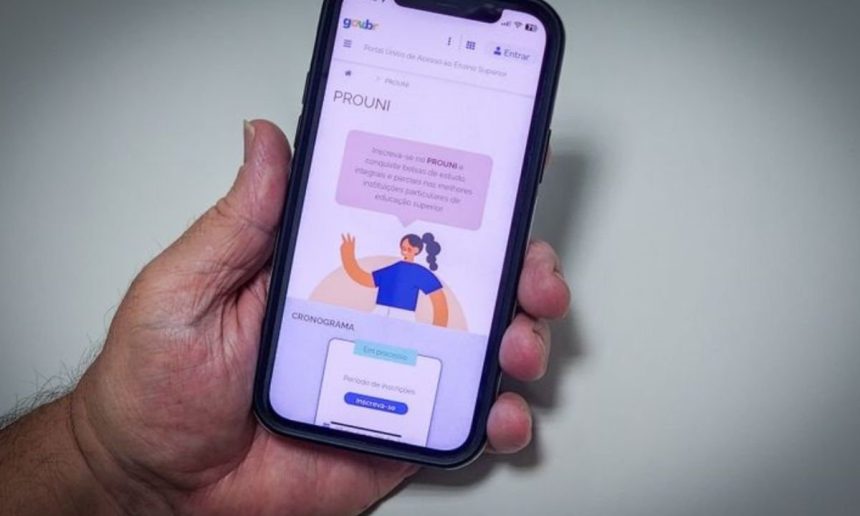 Smartphone com tela do PROUNI em primeiro plano, com detalhes sobre bolsas de estudo.
