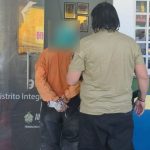 Suspeito preso em flagrante pela polícia, com as mãos algemadas