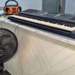 Teclado, rádio e ventilador sobre um balcão.