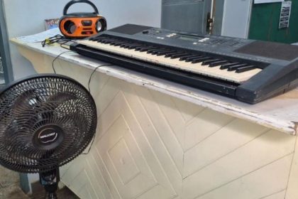 Teclado, rádio e ventilador sobre um balcão.