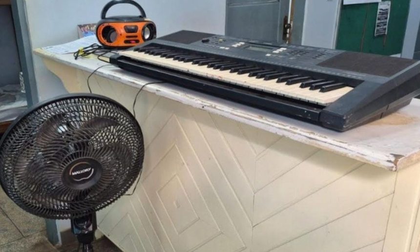 Teclado, rádio e ventilador sobre um balcão.