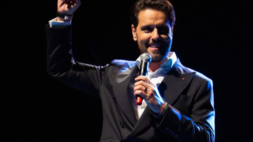 Thiago Arancam no palco, segurando um microfone e sorrindo.