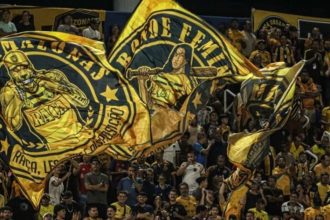 Torcedores do Amazonas FC com bandeiras personalizadas no estádio.