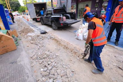 Trabalhadores em obra de infraestrutura urbana no centro de Manaus, com veículos de apoio.