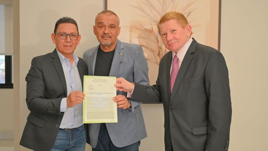 Três homens sorrindo segurando um documento oficial em uma sala com o documento sobre o novo Fórum de Silva