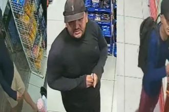 Três suspeitos de assalto em loja de conveniência, com roupas escuras e bonés.