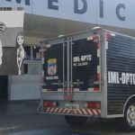 Veículo do IML em frente a um prédio, com homem em preto e branco e bandeira no fundo