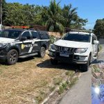 Veículos da polícia em cena de crime, com homem correndo e imagem de corpo no canto inferior.